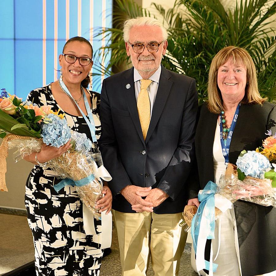 two women holding bouquets pose with the chancellor.